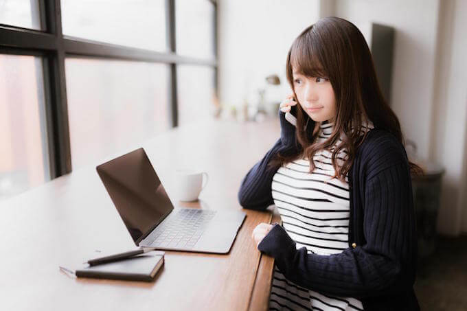 パソコンと電話で調べ物する女性